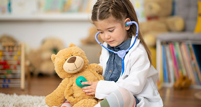 an image of a little girl using a stethoscope on a teddy bare
