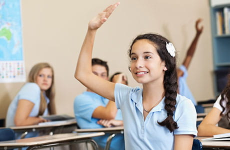 an image of a young girl raising her hand in class