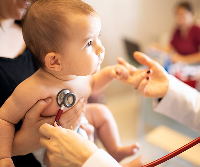 A pediatric pulmonary specialist uses a stethoscope to ensure a baby is breathing easily.