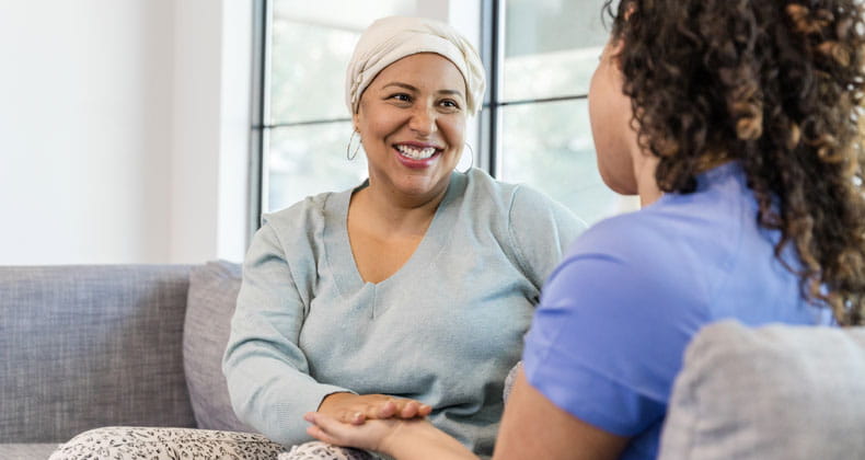 Two women sitting on a couch smiling through a conversation 