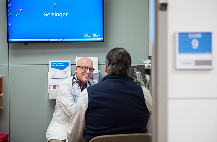 Un médico está hablando con un paciente mayor sobre los resultados que se muestran en una carpeta