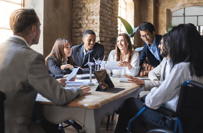 Un grupo de empleados conversan alrededor de una gran mesa de reuniones