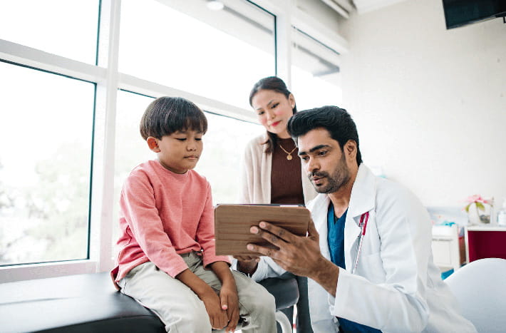 A doctor discusses results with a child in an exam room