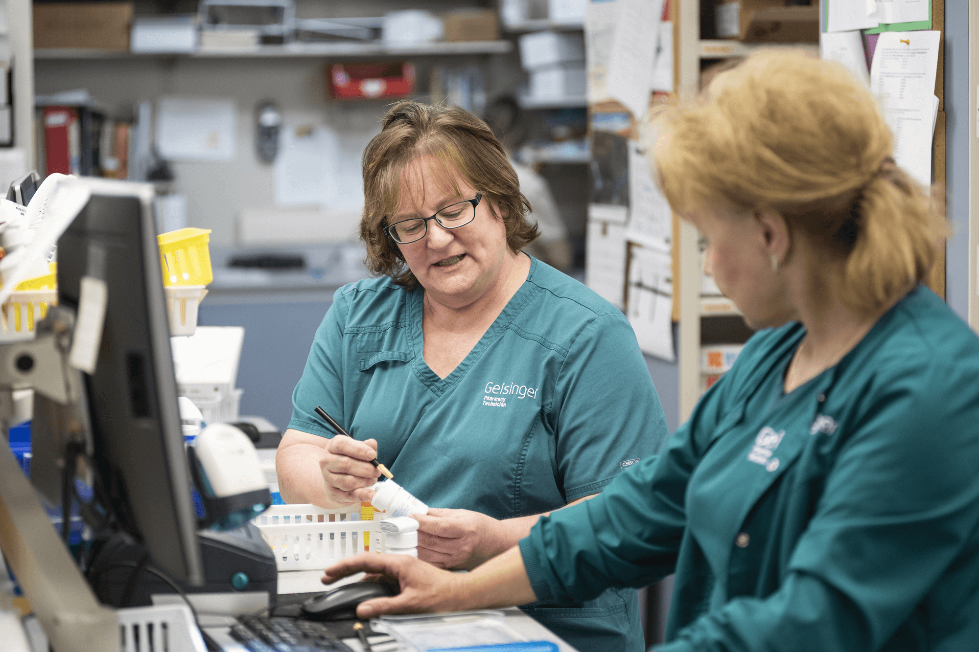 Two nurses discuss a prescription behind a counter