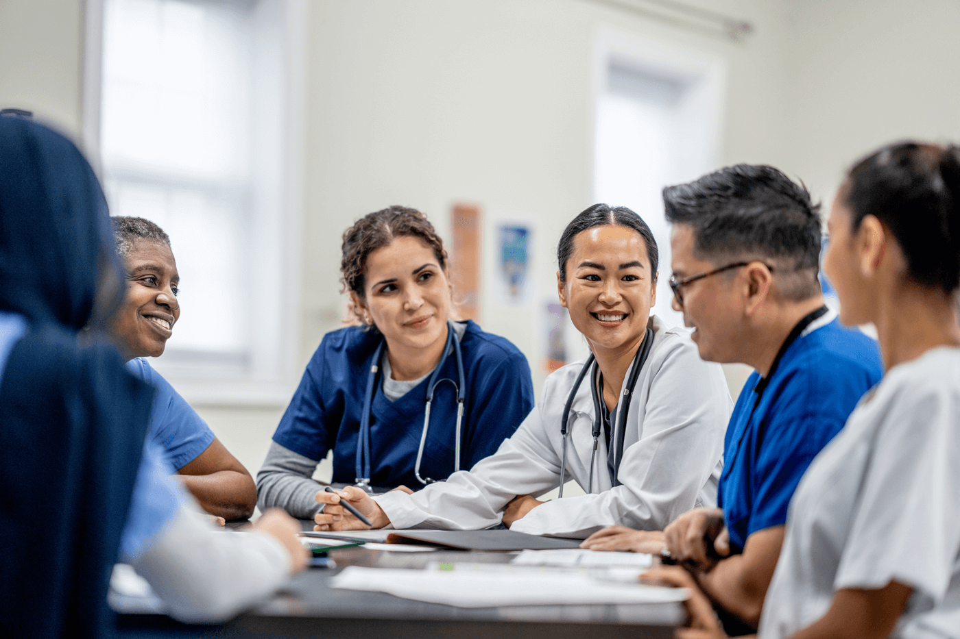 A group of nurses and doctors debrief in a meeting room