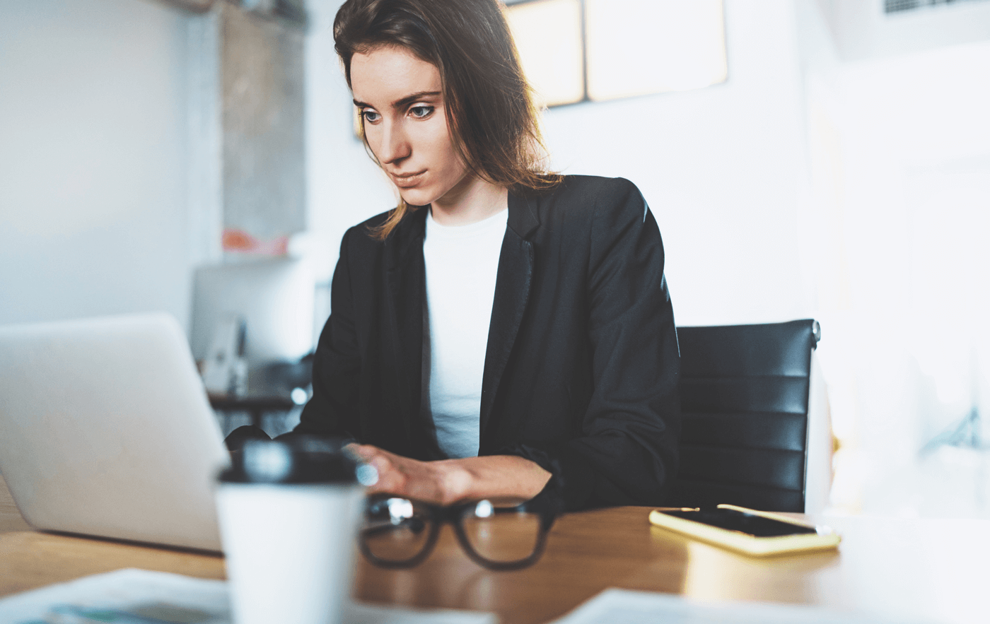 A woman in an office works on a laptop