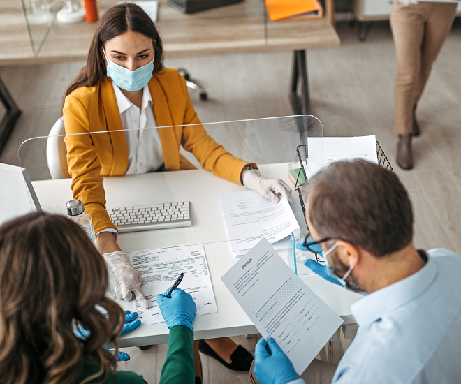 Couple reviewing contract with broker wearing mask and gloves