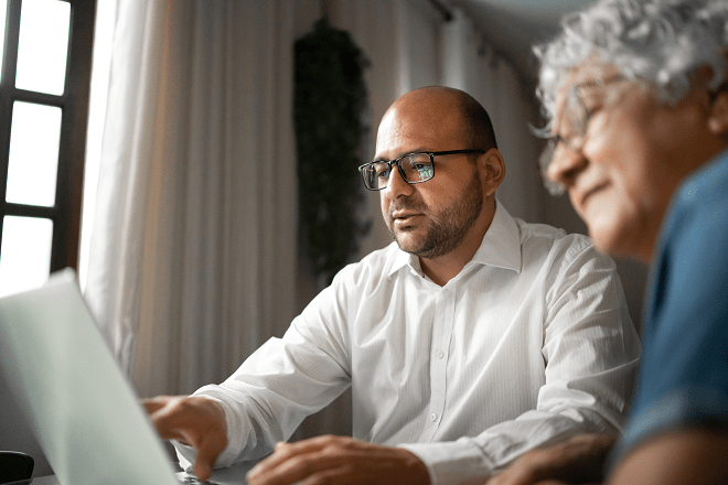 Senior woman reviewing document on laptop with broker