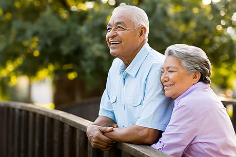 Older couple on a bridge looking out onto the stream.