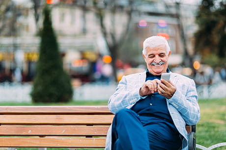 A Medicare Advantage member checking his phone on a park bench