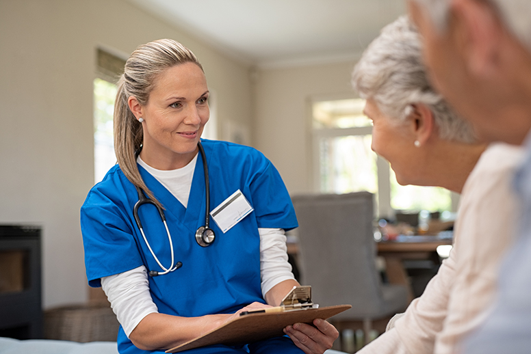 senior couple at home with nurse learning about wellness methods
