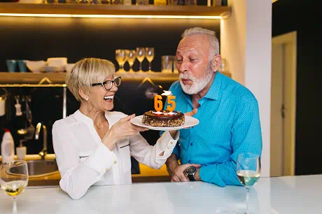 an older couple blowing out candles on a birthday cake