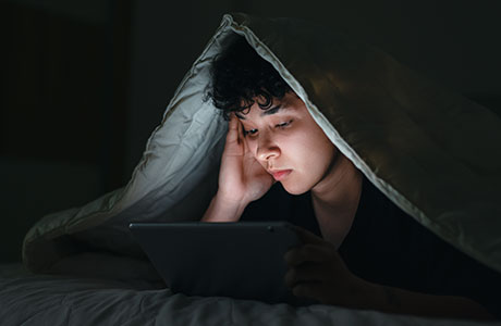 an image of a young boy looking at a tablet in bed