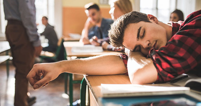 an image of a young boy asleep at his desk in class