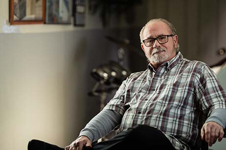 Neil sitting in a sofa chair smiling