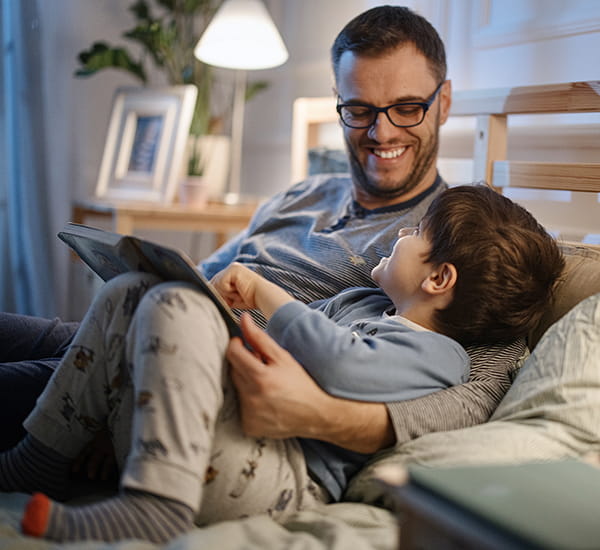 Father reading a bedtime story to his son before bed