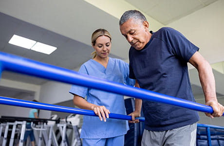 a female physical therapist helping a older male patient