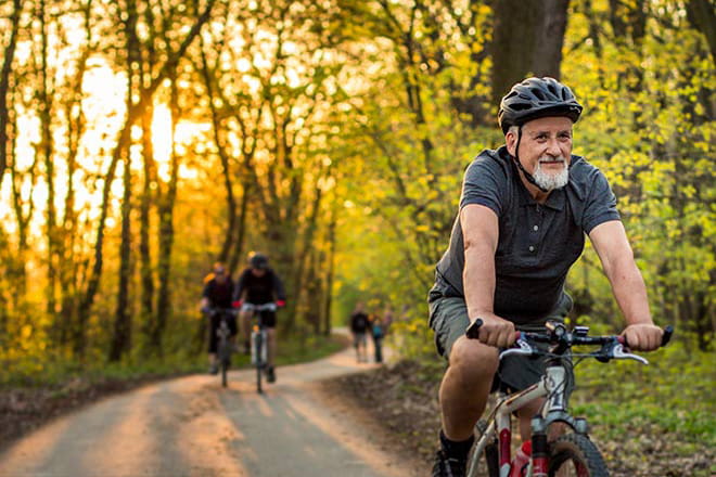 Man biking with friends outside on a trail