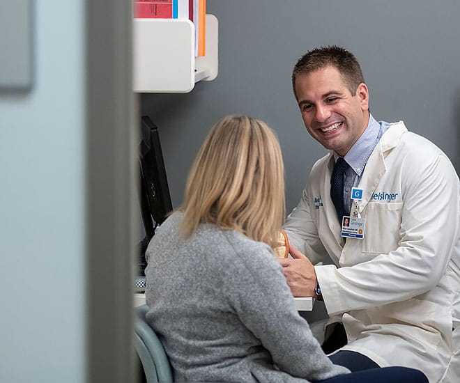 A provider consults with a patient in an examination room.