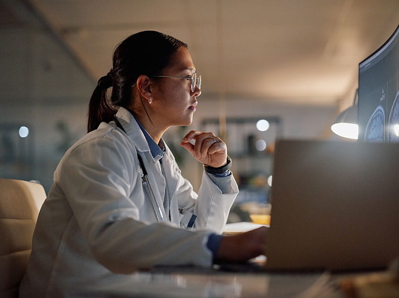 A healthcare worker looking at a computer monitor researching