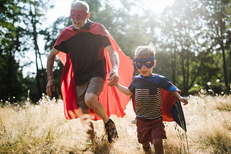 Grandfather running with his grandson dressed up as super heros