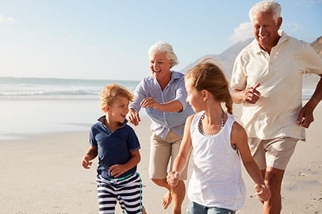 grandparents running on the beach with their two grandchildren