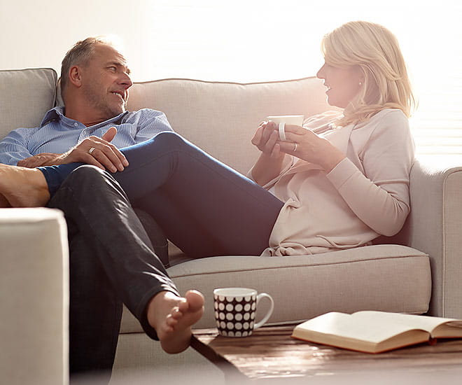 Relaxed couple on couch discussing options for liposuction