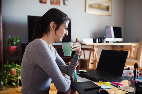 Cheerful young woman with hearing aid using a computer to find a doctor