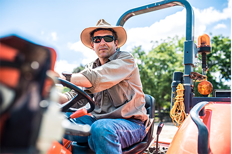 young farmer with sunglasses on mowing the yard