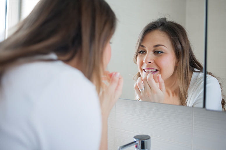 Woman looking at her teeth in mirror