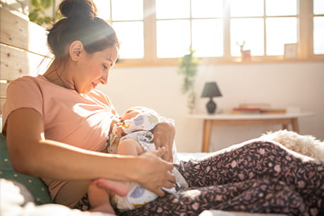 mother breastfeeding her child in a bedroom