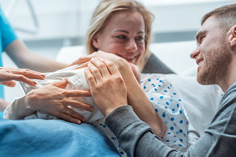 New mother holding baby after delivery looking at male counterpart