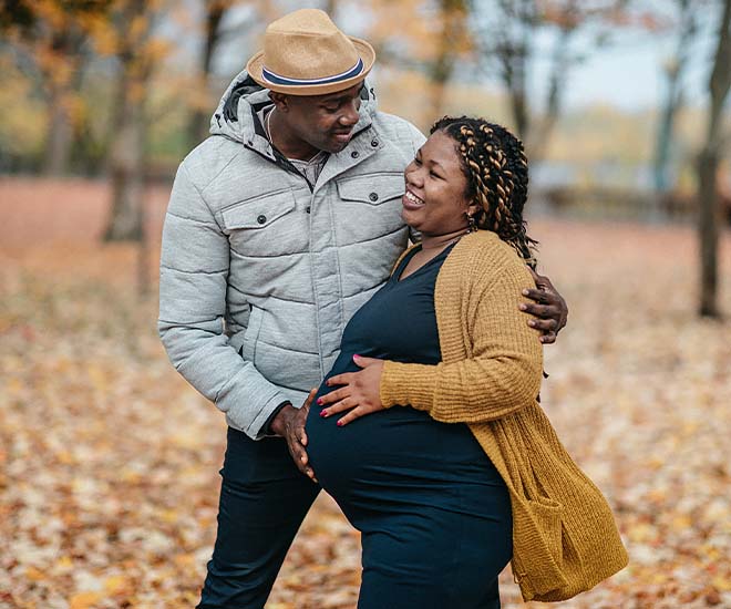 Pregnant woman and man enjoy an autumn walk in the woods.