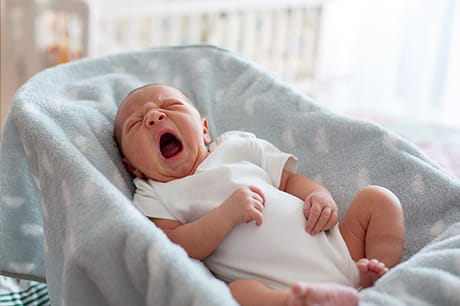 newborn baby yawning in a crib