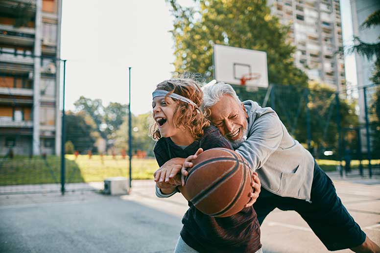 Grandfather and Grandson laughing playing basketball 