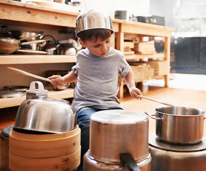 child in kitchen using pots and pans as drums