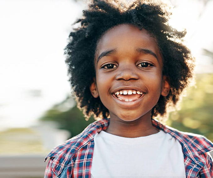 cheerful little boy smiling outside during the day