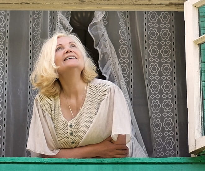 Woman looking outside her window hopefully smiling
