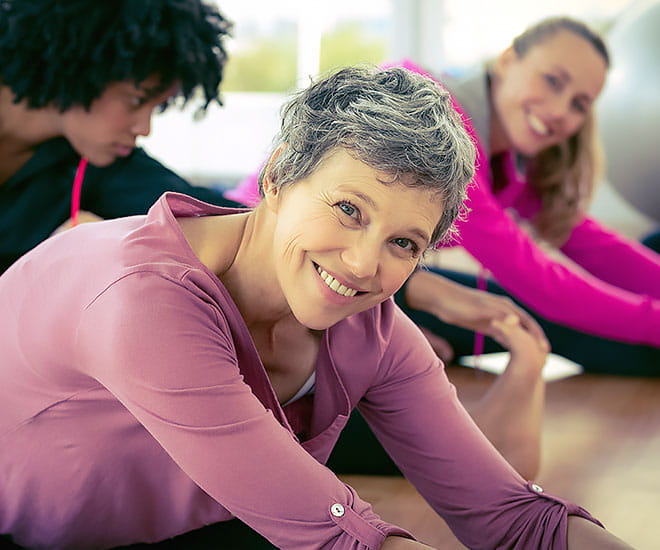 Middle-aged woman doing a pelvic stretch on the floor.