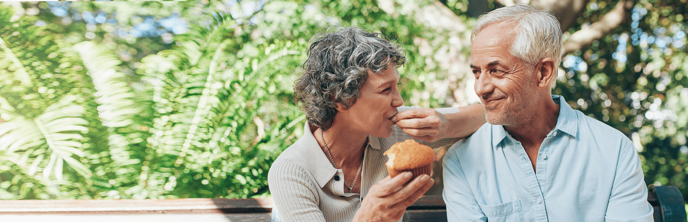 Mid 60s male and female couple sitting on a bench smiling