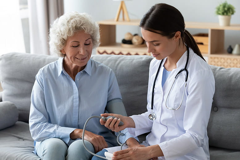 oung female nurse measure blood pressure check old grandma