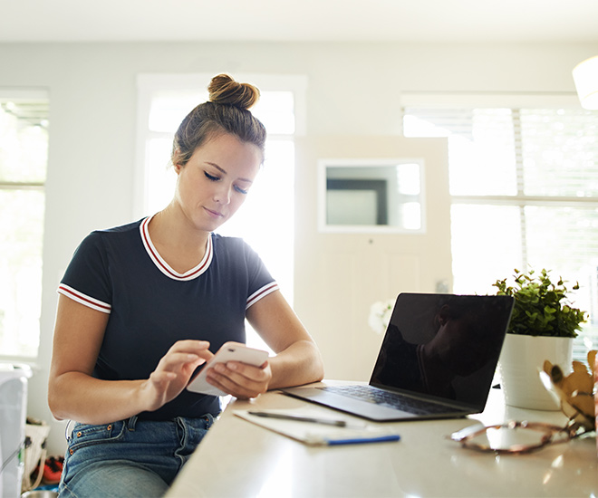 Woman on phone near laptop at home