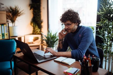 Man working from home at a desk and on the phone.