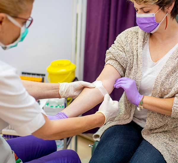 Woman donating blood while wearing a mask