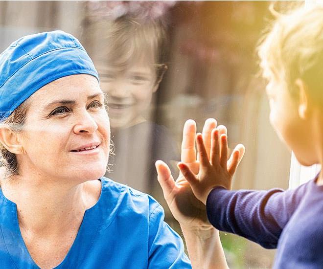 Mature Healthcare worker posing seeing her son with a window glass separating them to avoid possible contagion