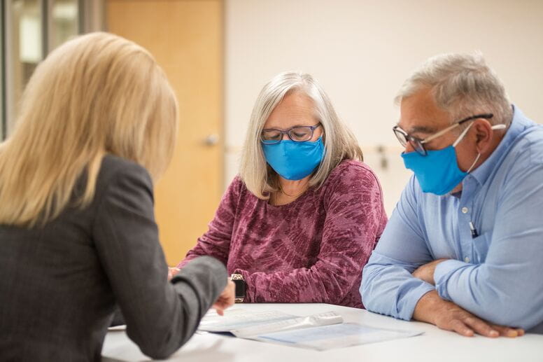 Masked couple meeting with representative to discuss health plan coverage