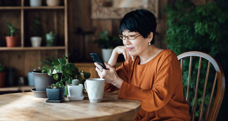 Woman sitting at table looking at phone.