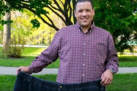 James Ross holds up his old pants after loosing 300 pounds following bariatric surgery.
