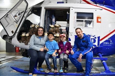 Kristy Creasy, Tyler Creasy, Aly Creasy and Scott Lynn sitting on the leg of a helicopter. 