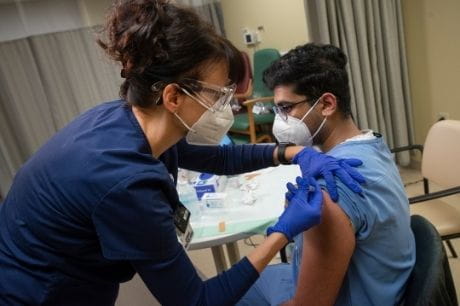 Nurse gives doctor vaccine.